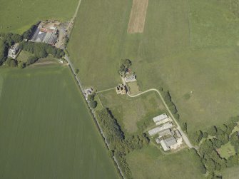 Oblique aerial view centred on the remains of the tower-house with the farmsteading adjacent, taken from the SE.