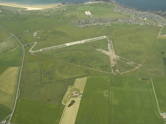 General oblique aerial view centred on the airfield with the village in the distance, taken from the SE.