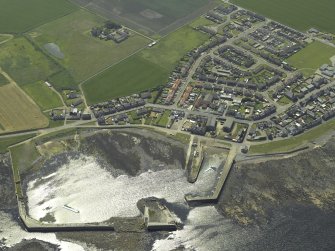 General oblique aerial view of the village centred on the harbour, taken from the NE.
