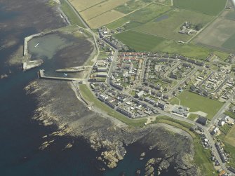 General oblique aerial view of the village centred on the harbour, taken from the NNW.