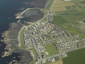 General oblique aerial view of the village centred on the harbour, taken from the NW.