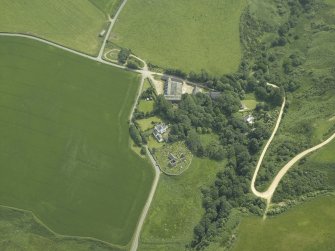 Oblique aerial view centred on the remains of the church and burial ground with the hotel and former manse adjacent, taken from the N.