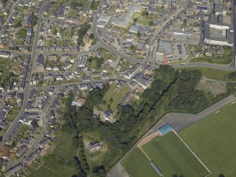 Oblique aerial view centred on the remains of the church and the burial-ground, taken from the W.