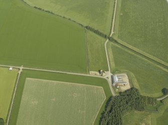 Oblique aerial view centred on the remains of the castle and the farmsteading, taken from the WNW.