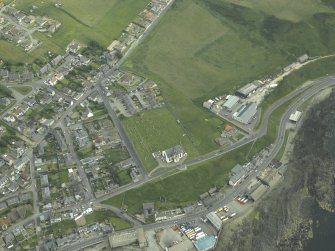 Oblique aerial view centred on the church with the former railway station and fishing station adjacent, taken from the N.