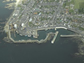 Oblique aerial view centred on the harbour, harbour basin, beacon, pier and jetties, taken from the NW.