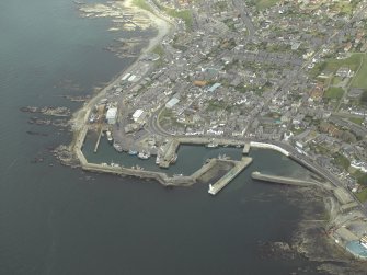 Oblique aerial view centred on the harbour, harbour basin, beacon, pier and jetties, taken from the WNW.