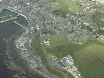 Oblique aerial view centred on the church with the former railway station and fishing station adjacent, taken from the SW.