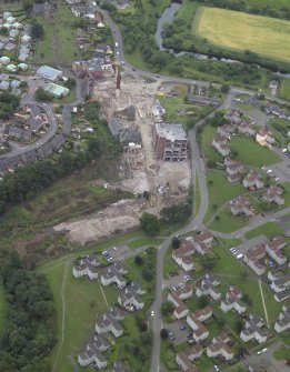 Oblique aerial view centred on the whisky distillery during demolition with the church, churchyard and cemetery adjacent, taken from the WSW.
