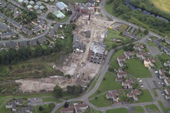 Oblique aerial view centred on the whisky distillery during demolition, taken from the SW.