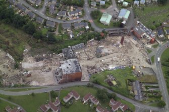 Oblique aerial view centred on the whisky distillery during demolition with the cemetery adjacent, taken from the S.