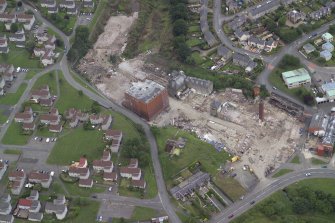 Oblique aerial view centred on the whisky distillery during demolition, taken from the ESE.