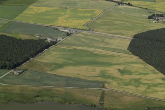 General oblique aerial view centred on the cropmarks of the roundhouses, pits and possible souterrain with the cropmarks of the ring-ditch and the farmsteading adjacent, taken from the SE.