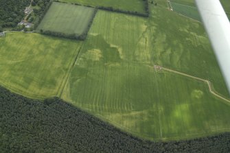 General oblique aerial view centred on the cropmarks of the rig and pits with the country house adjacent, taken from the WNW.