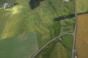 Oblique aerial view centred on the cropmarks of the ring-ditches and roundhouses, taken from the WSW.