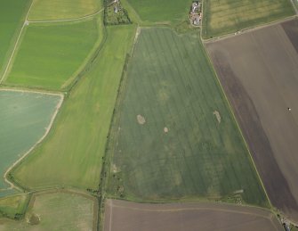 Oblique aerial view centred on the cropmarks of the rig, field boundary and possible ring-ditches with the farmhouse and farmsteading adjacent, taken from the WSW.