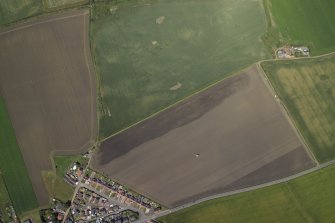 Oblique aerial view centred on the cropmarks of the rig, field boundary and possible ring-ditches with the farmhouse and farmsteading adjacent, taken from the S.