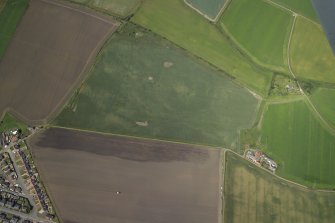 Oblique aerial view centred on the cropmarks of the rig, field boundary and possible ring-ditches with the farmhouse and farmsteading adjacent, taken from the SE.