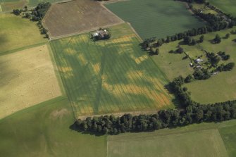 Oblique aerial view centred on the cropmarks of the Roman fortress and ring-ditch with the country house, farmhouse and farmsteading adjacent, taken form the NNW.