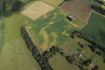 Oblique aerial view centred on the cropmarks of the Roman fortress and ring-ditch with the country house, farmhouse and farmsteading adjacent, taken form the W.