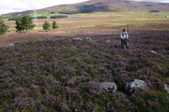 View of hut-circle, taken from SW; Mr J Hepher (RCAHMS) in picture.