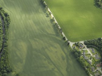 Oblique aerial view centred on the cropmarks of the rig, pits and possible souterrain and the field boundaries with the gate-lodge adjacent, taken from the WSW.