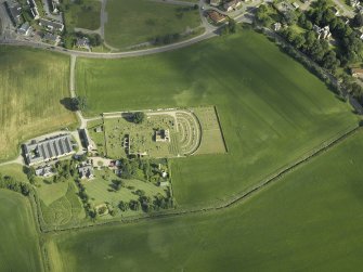 Oblique aerial view centred on the remains of the abbey and burial-ground and the farmsteading, taken from the SSE.
