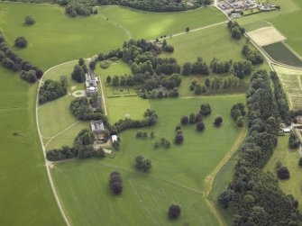 Oblique aerial view centred on the country house, tower-house, farmhouse, farmsteading, cottages and stables, taken from the W.