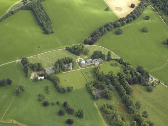 Oblique aerial view centred on the country house, tower-house, farmhouse, farmsteading, cottages and stables, taken from the S.