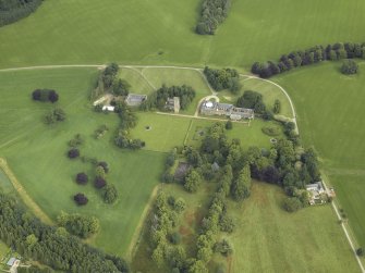 Oblique aerial view centred on the country house, tower-house, farmhouse, farmsteading, cottages and stables, taken from the SSE.