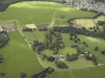 General oblique aerial view centred on the country house, tower-house, farmhouse, farmsteading and stables with the walled garden, farmsteading and kennels adjacent, taken from the NNW.