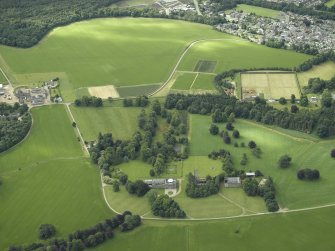 General oblique aerial view centred on the country house, tower-house, farmhouse, farmsteading and stables with the walled garden, farmsteading and kennels adjacent, taken from the NW.