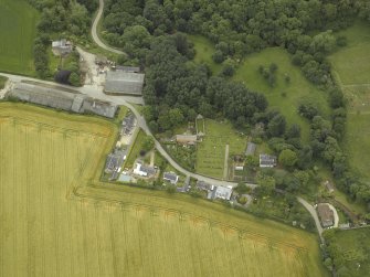 Oblique aerial view centred on the remains of the church, burial ground and tower-house, taken from the W.