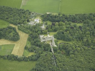 Oblique aerial view centred on the country house, stables and bridge, taken from the WSW.