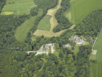 Oblique aerial view centred on the country house, stables and bridge, taken from the SW.