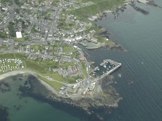 Oblique aerial view of the village centred on the harbours, taken from the NE.
