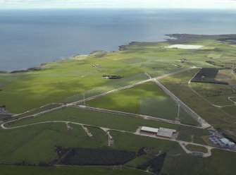 General oblique aerial view centred on the remains of the airfield and the wind farm, taken from the WSW.