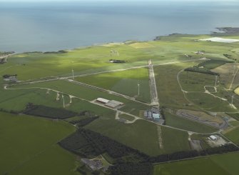 General oblique aerial view centred on the remains of the airfield and the wind farm, taken from the SW.