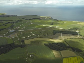 General oblique aerial view centred on the remains of the airfield and the wind farm, taken from the SE.