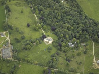 Oblique aerial view centred on the country house with the farmhouse and farmsteading adjacent, taken from the SSW.