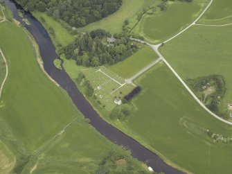 Oblique aerial view centred on the remains of the church and the burial-ground with the manse adjacent, taken from the SE.