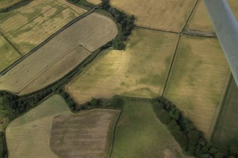General oblique aerial view centred on the cropmarks of the ring-ditch, taken from the SE.