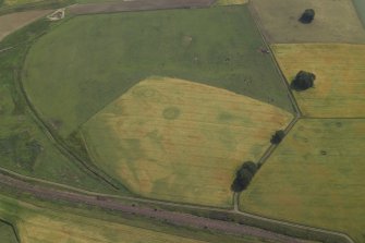 Oblique aerial view centred on the cropmarks of the enclosure and ring-ditch with the cropmarks of the Roman fort adjacent, taken from the W.