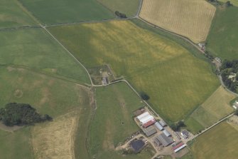 Oblique aerial view centred on the cropmarks of the enclosure, rig and possible settlement with the farmsteading adjacent, taken from the NE.