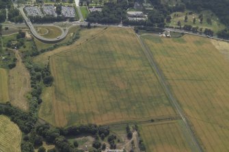 Oblique aerial view centred on the cropmarks of the settlement and fort with the church adjacent, taken from the N.
