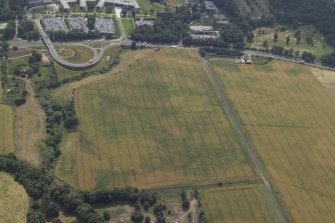 Oblique aerial view centred on the cropmarks of the settlement and fort with the church adjacent, taken from the N.