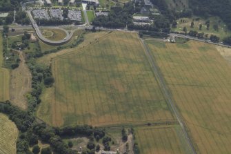 Oblique aerial view centred on the cropmarks of the settlement and fort with the church adjacent, taken from the N.