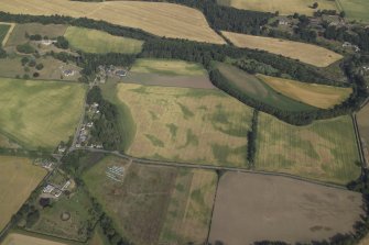 Oblique aerial view centred on the cropmarks of the pit-alignments with the church, burial-ground, manse and cropmarks of the possible enclosure adjacent, taken from the SE.