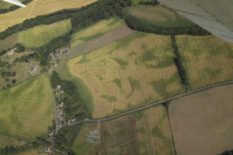 Oblique aerial view centred on the cropmarks of the pit-alignments with the church, burial-ground, manse and cropmarks of the possible enclosure adjacent, taken from the S.