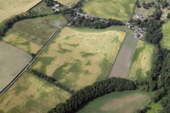 Oblique aerial view centred on the cropmarks of the pit-alignments with the church, burial-ground, manse and cropmarks of the possible enclosure adjacent, taken from the NE.
